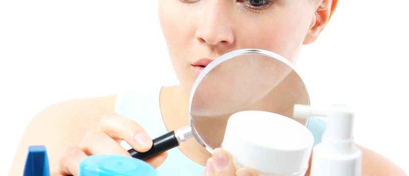 A woman stands at the client shelf and looks at the composition of creams